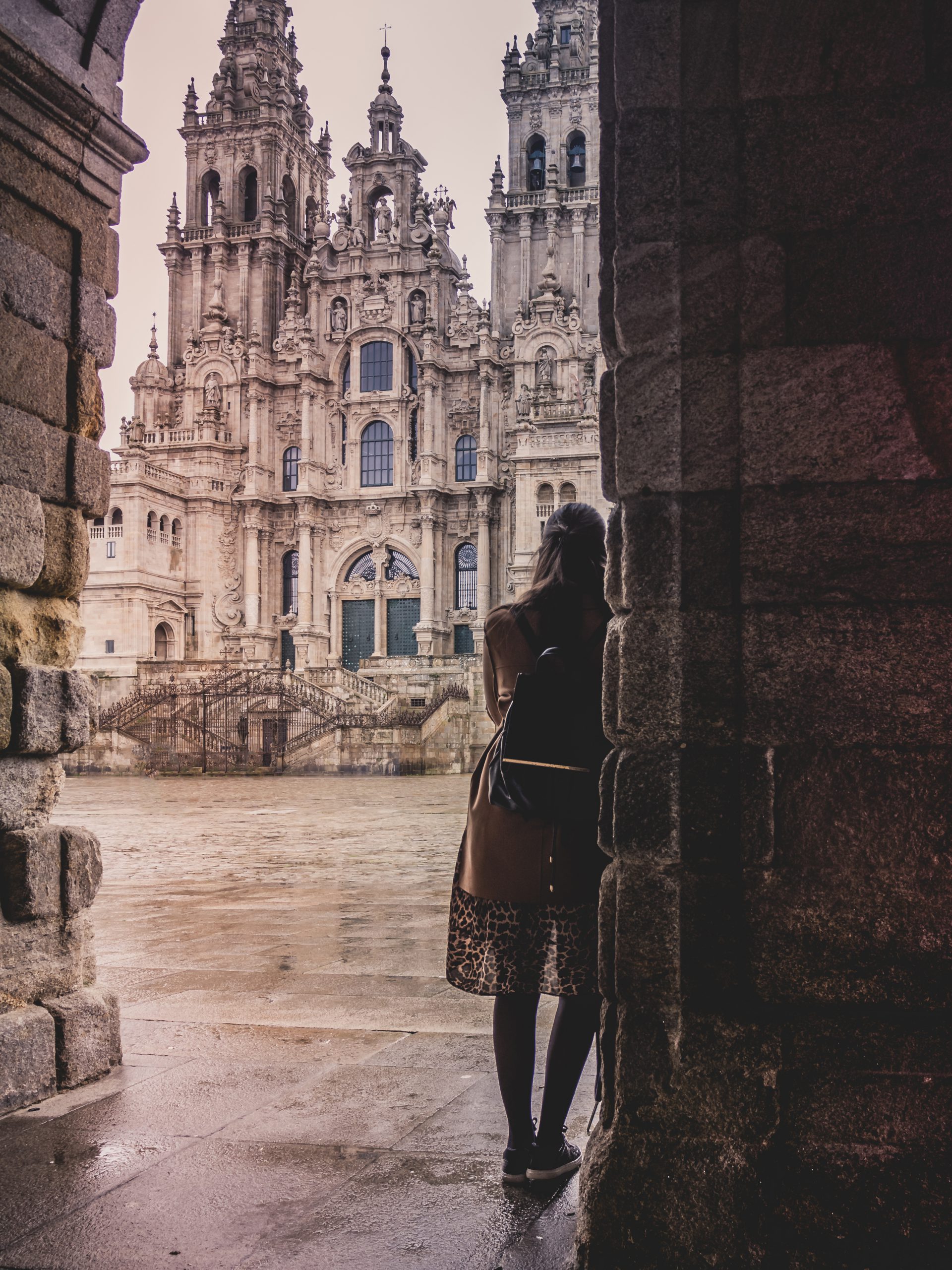 Vertical shot of a stylish female in the Cathedral of Santiago de Compostela in Spain on a rainy day